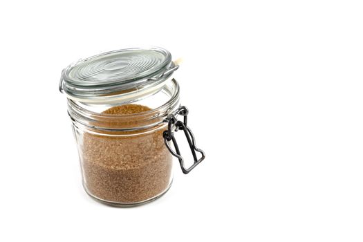 Brown cane sugar in glass jar isolated on white background. 