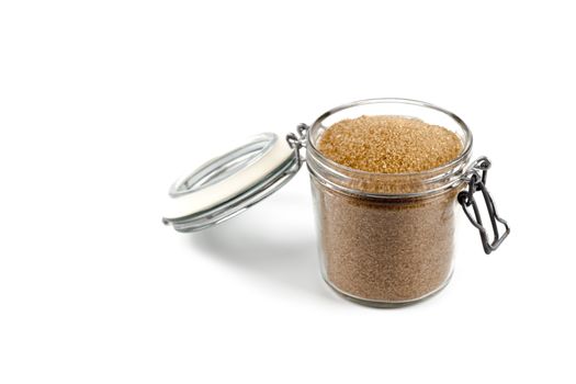 Brown cane sugar in glass jar isolated on white background.