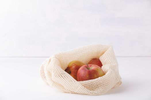 Red apples in reusable cotton bags. Copyspace