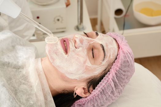 Young woman in beauty salon does rejuvenating, toning procedure darsonval on the face.