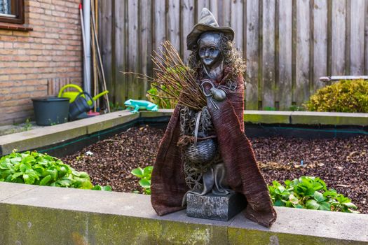 spooky witch statuette in a garden, outdoor halloween decorations, fairy tale characters