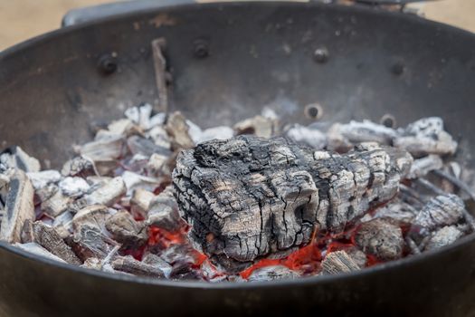 Hot charcoal burns in the grill with embers