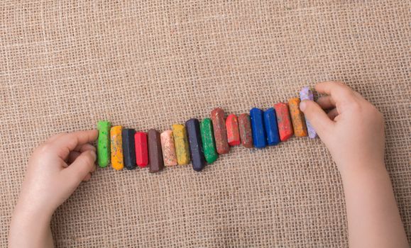 Toddlers hand putting crayons in line on canvas