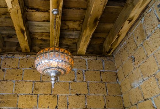 Silver moroccan lighted lantern hanging on a wooden roof, traditional home interiors and decorations