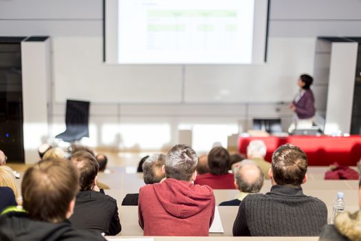 Woman giving academic presentation in lecture hall at university.