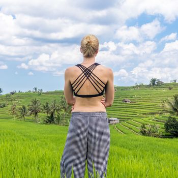Relaxed casual sporty woman enjoying pure nature at beautiful green rice fields on Bali.