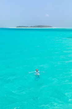 Woman snorkeling in clear shallow sea of tropical lagoon with turquoise blue water.