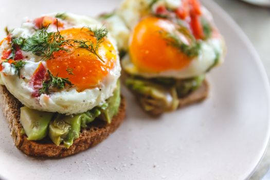 Breakfast served of two toasts with avocado, fried eggs with veg