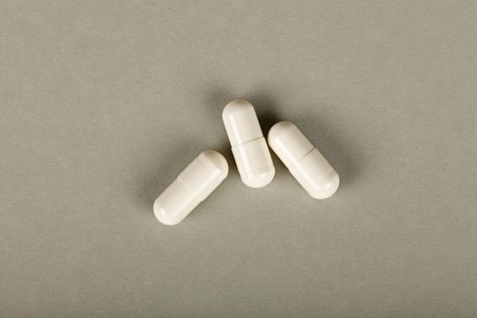 Close up three gel cap pills over grey background