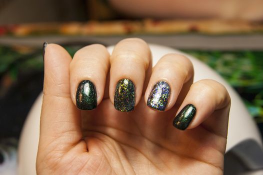 beautiful green manicure, nail polish on nails of different shades of green, with a slight sheen and large shimmer