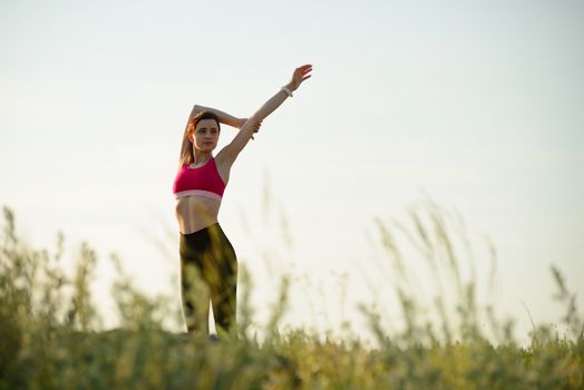 Woman Doing Stretching Outdoor. Warm up Exercise in the Summer Evening. Sport and Healthy Active Lifesyle Concept.