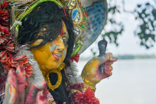 A Devi Maa Durga sadly looks down with tousled hair while tears flow the eyes during Durga Maa visarjan or immersion at Ganga or Ganges river. It reflects the sad moments for all bengali people.