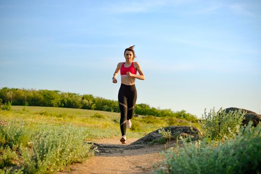 Young Beautiful Woman Running on the Mountain Trail in the Hot Summer Evening. Sport and Active Lifestyle.