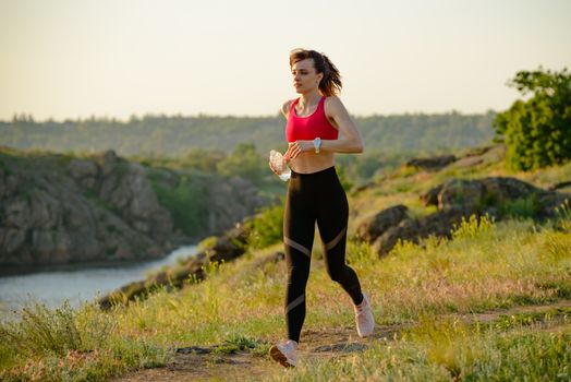 Young Beautiful Woman Running on the Mountain Trail in the Hot Summer Evening. Sport and Active Lifestyle.