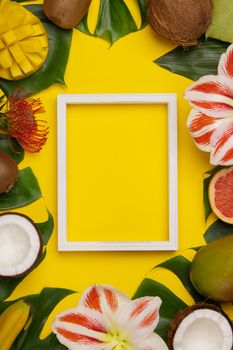 Creative flat lay with tropical fruits and plants and white frame for your text
