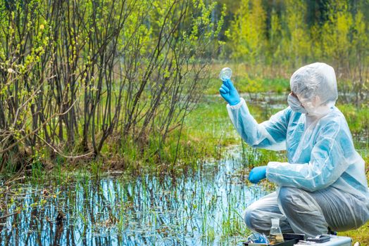 woman studies water and plants from forest lake, chemical compos