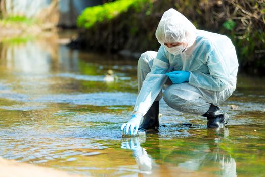 scientist researcher in protective suit takes water for analysis