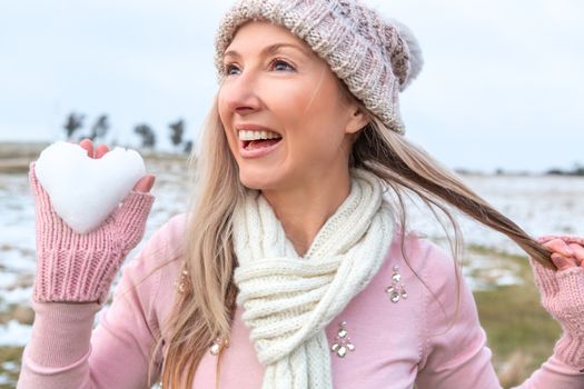 Exuberant woman holding a heart of snow