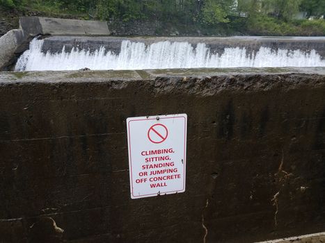no climbing sitting or standing or jumping off wall sign and waterfall
