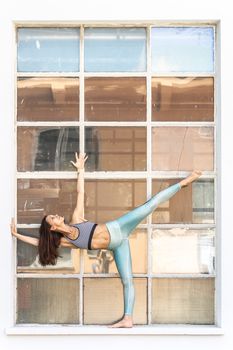 Fit sporty active girl in fashion sportswear doing yoga fitness exercise in front of gray wall, outdoor sports, urban style