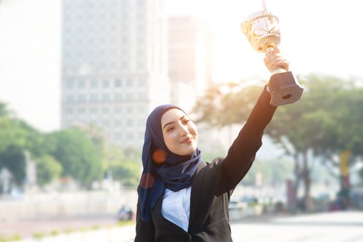 Businesswoman hand holding a trophy