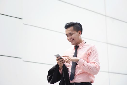 Businessman reading on mobile phone and smile while walking outdoor.