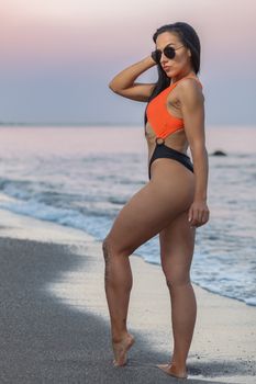 Fitness girl posing with a beautiful black and orange bikini