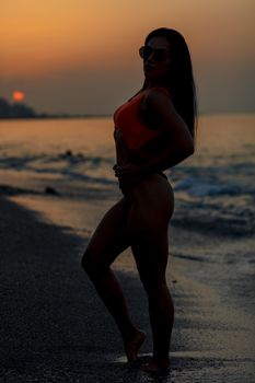 Fitness girl posing with a beautiful black and orange bikini