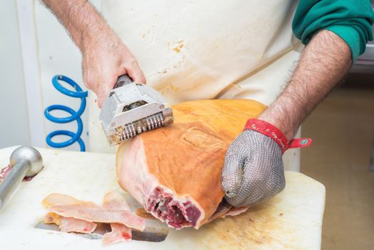 Close up of worker hands in the industrial process of cutting iberian ham