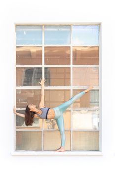 Fit sporty active girl in fashion sportswear doing yoga fitness exercise in front of gray wall, outdoor sports, urban style