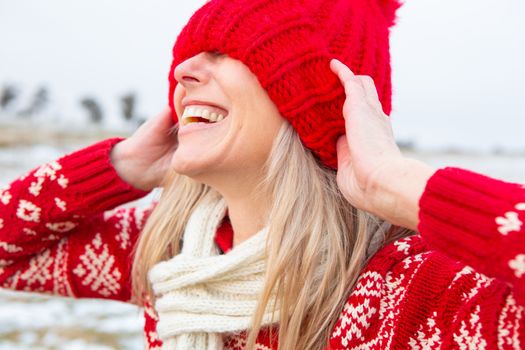 Happy woman outdoors pulling beanie over eyes