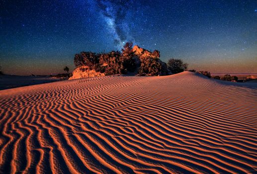 Sand dunes under starry night sky