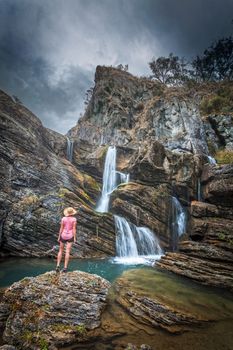 Traveller stands in awe, moody skies, limestone cliffs, waterfalls and blue waterholes
