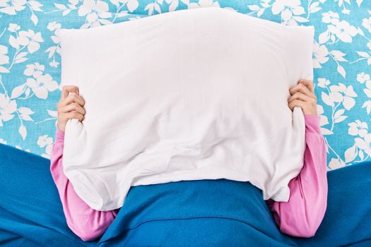 Young girl in bed with a pillow on top of her head
