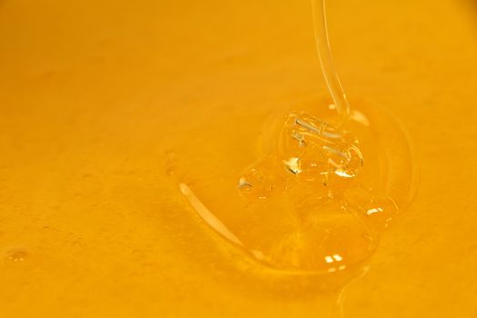 Close up pouring fresh fluid honey in bowl