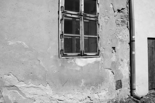 View of an old house with cracks on the wall and window, black and white photo.