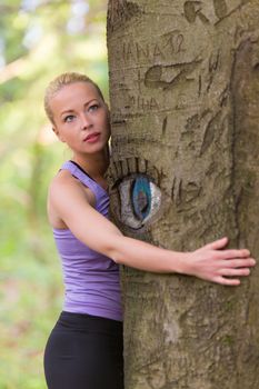 Young woman hugging a tree.