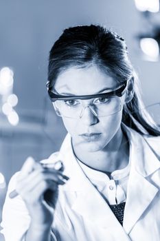 Portrait of a confident female researcher in life science laboratory writing structural chemical formula on a glass board.