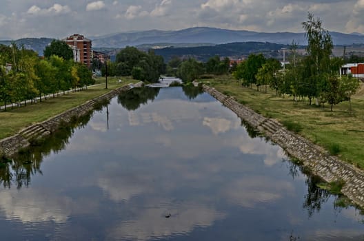 Summer landscape of river valley Bregalnica with place for relax and trees through town Delchevo among Maleshevo and Osogovo mountains