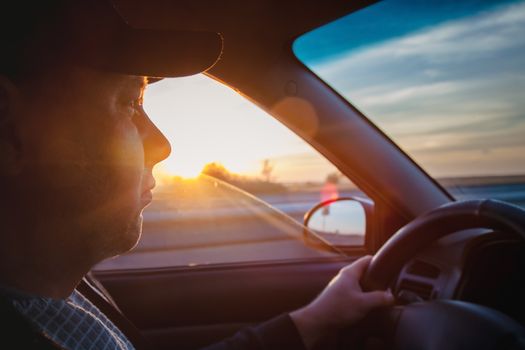 man driving a car at sunset-dawn, close-up, blur. Concept, road trips and travel, freedom of movement