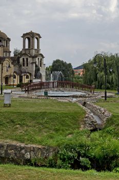 General view of public garden  in  residential district with new orthodox church, artificial ponds, fountain and bridges, town Delchevo