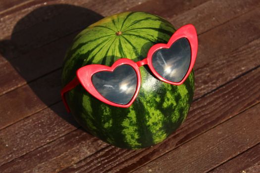 a melon with sunglasses on brown boards