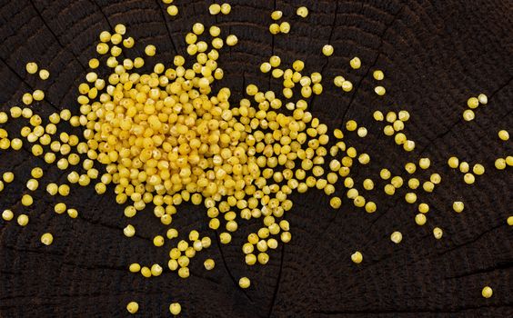 Heap of millet groats on black wooden background. Top view