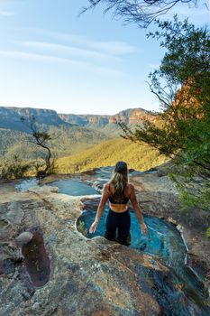 Adventure female enjoying plunge pools at end of canyon with mountain vista