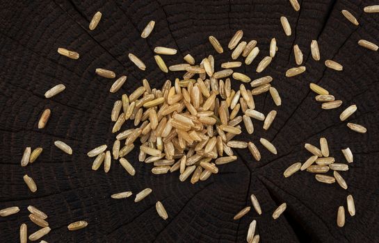 Brown rice groats on black wooden background. Top view
