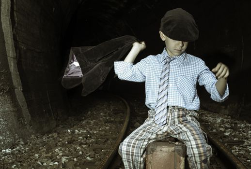 Child in vintage clothes sits on railway road