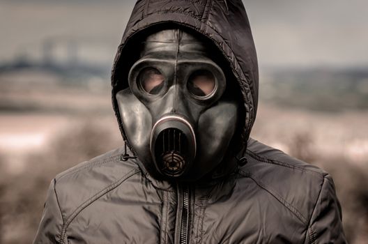 portrait of a man in a gas mask and a hood against the backgroun