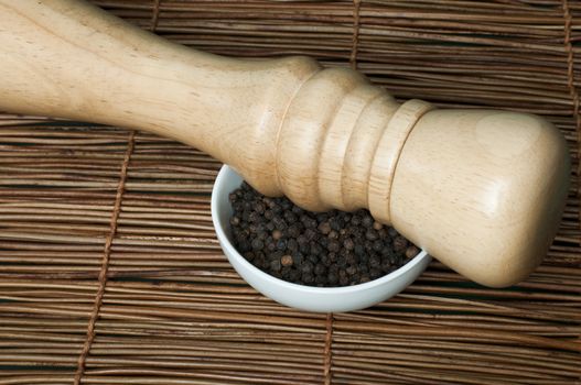 Bowl with black pepper and wooden pepper mill