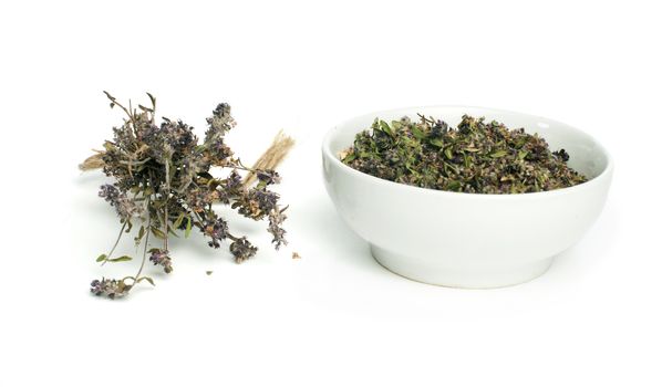 Dried thyme in a bowl and thyme twigs on white background