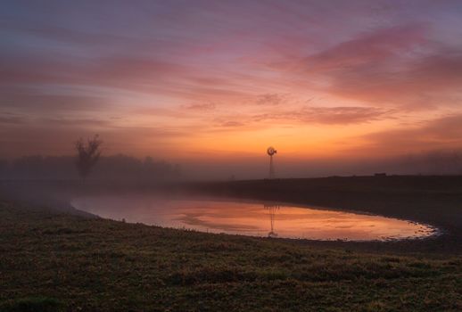 Red skies at dawn with light mist across rural farmlands